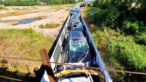 Tren choca con el techo de un puente y destruye los autos nuevos que transportaba